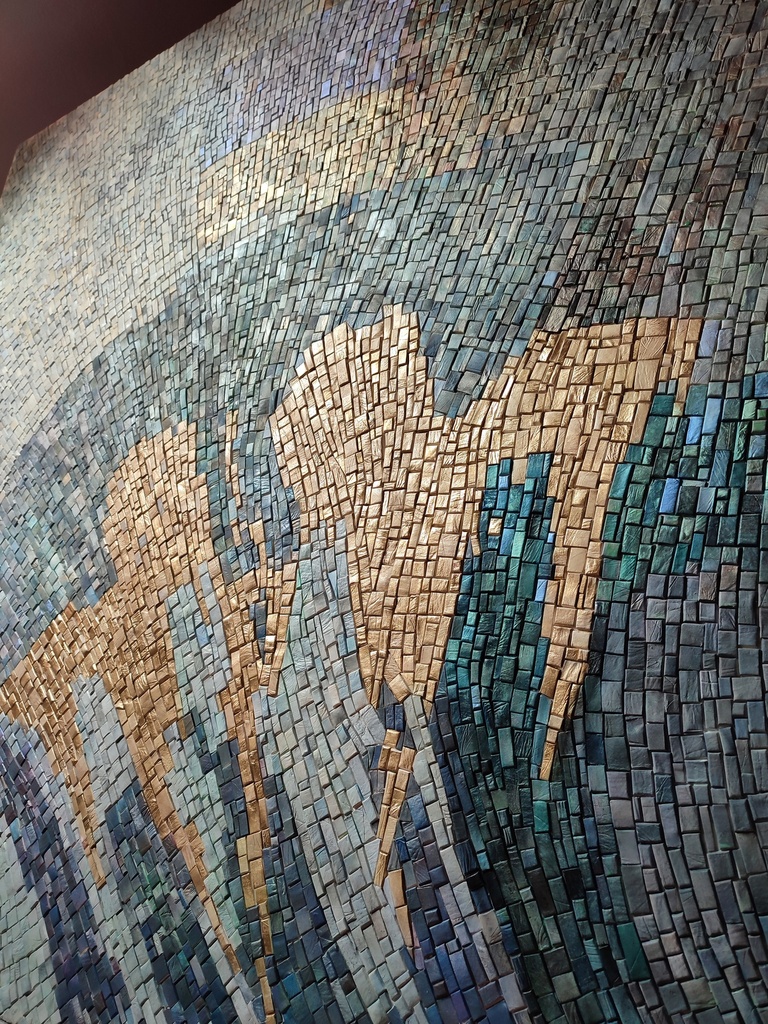Detail of teal mosaic wall art with abstract floral pattern in aqua, gray and gold tones