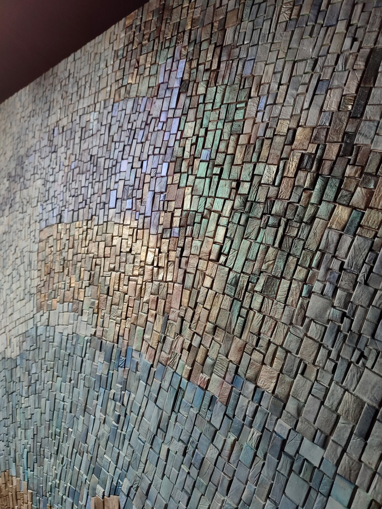 Detail of teal mosaic wall art with abstract floral pattern in aqua, green and gold tones
