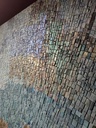 Detail of teal mosaic wall art with abstract floral pattern in aqua, green and gold tones
