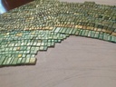 Close up of abstract mosaic wall art with taupe, grey, brown and light blue colors in textured wave pattern