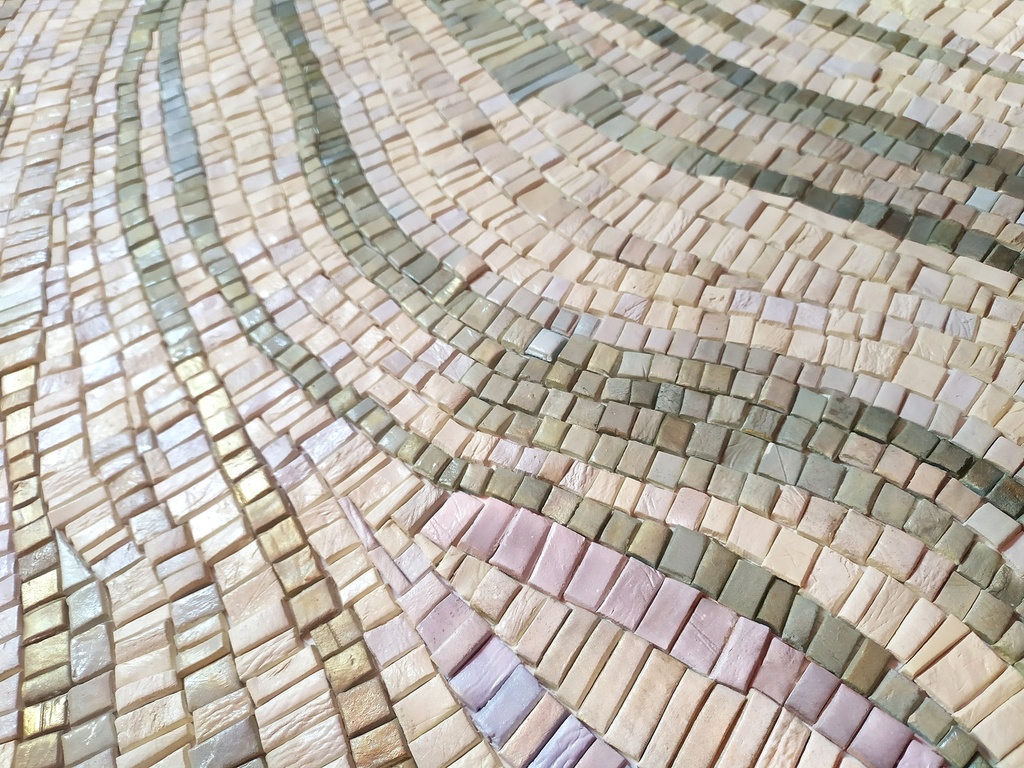 Close up of mosaic wall art with pastel green, lavender, and gold tones